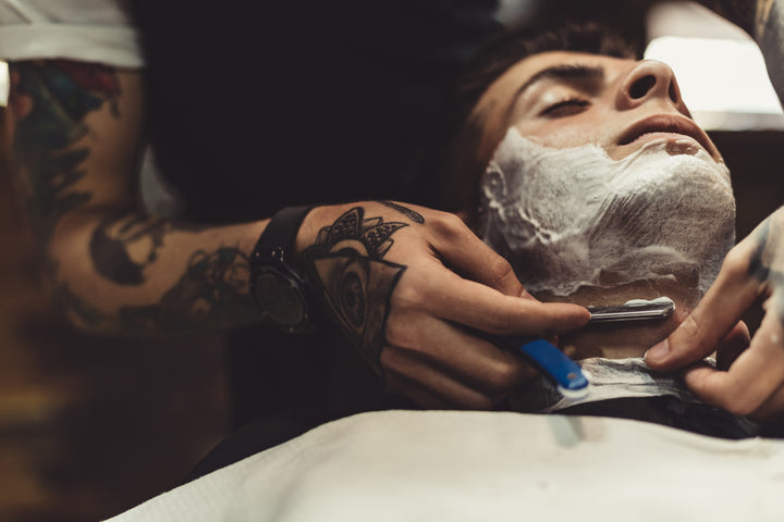 man getting straight razor shave from barber
