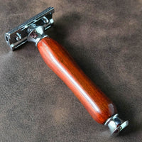 Safety razor with a traditional handle made from padauk on a brown leather surface