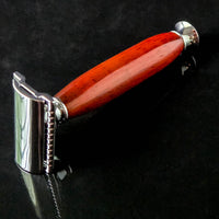 Shaving razor with a modern red handle made from padauk on a black reflective background