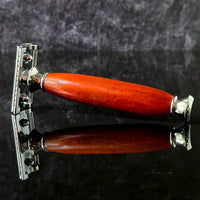 Shaving razor with a wooden handle made from padauk on a dark reflective background