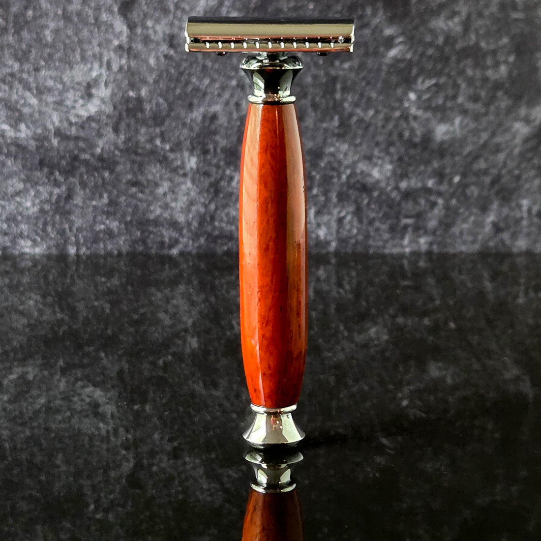 Shaving razor with a modern wooden handle made from padauk on a dark gray background