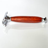 Shaving razor with a modern wooden handle made from padauk on a white reflective background