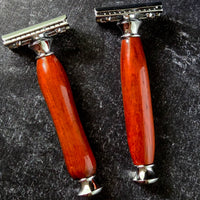 Two razors with traditional and modern handles made from padauk on a dark textured surface