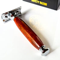 Safety razor with modern wooden handle made from padauk on a white background with a gift box in the background